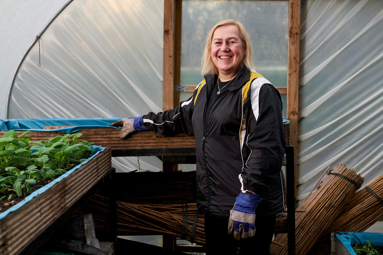 woman standing near green plants inside a greenhouse