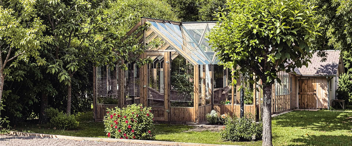 Wooden Nordwood greenhouse with tempered glass in a garden