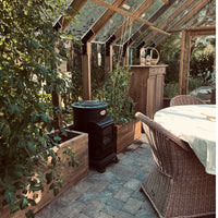 Greenhouse with plants, wooden furniture, and a table inside