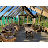 Outdoor patio area with wicker furniture and a wooden table under a wooden pergola.