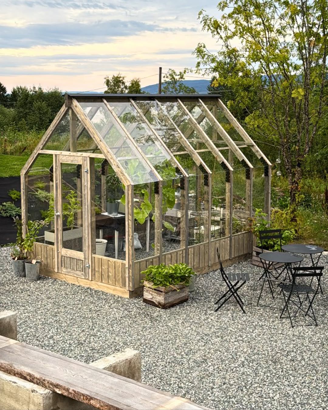 Greenhouse with outdoor seating area in a garden setting