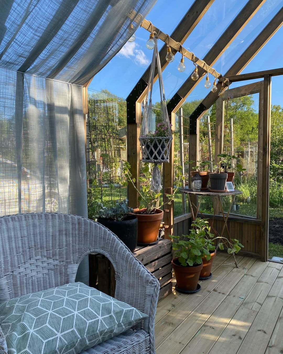 Outdoor patio area with wicker chair, plants, and a table under a wooden pergola.