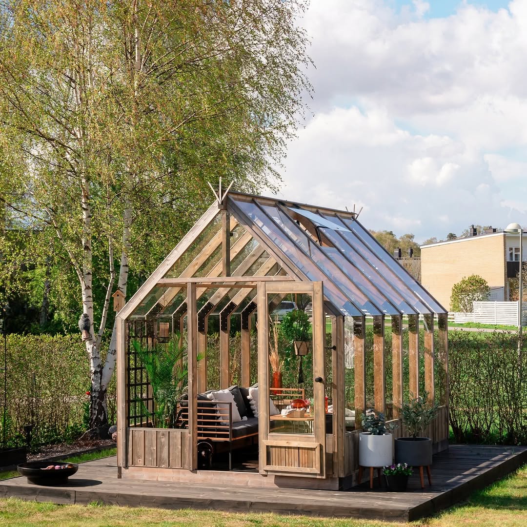 Wooden greenhouse with interior furniture in a garden setting