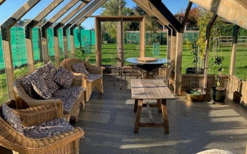 Outdoor patio area with wicker furniture and a wooden table on a sunny day.