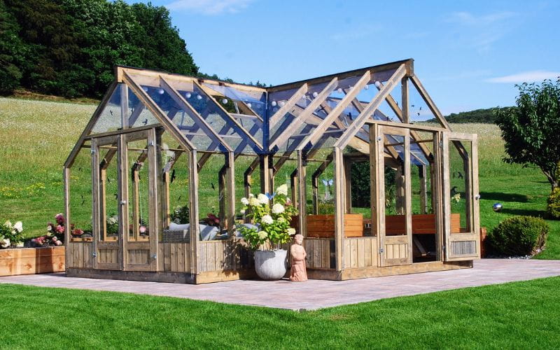 Wooden greenhouse with glass panels in a garden setting