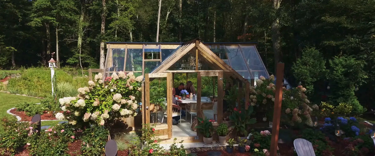 A Nordwood greenhouse among hydrangeas, a family at the table inside
