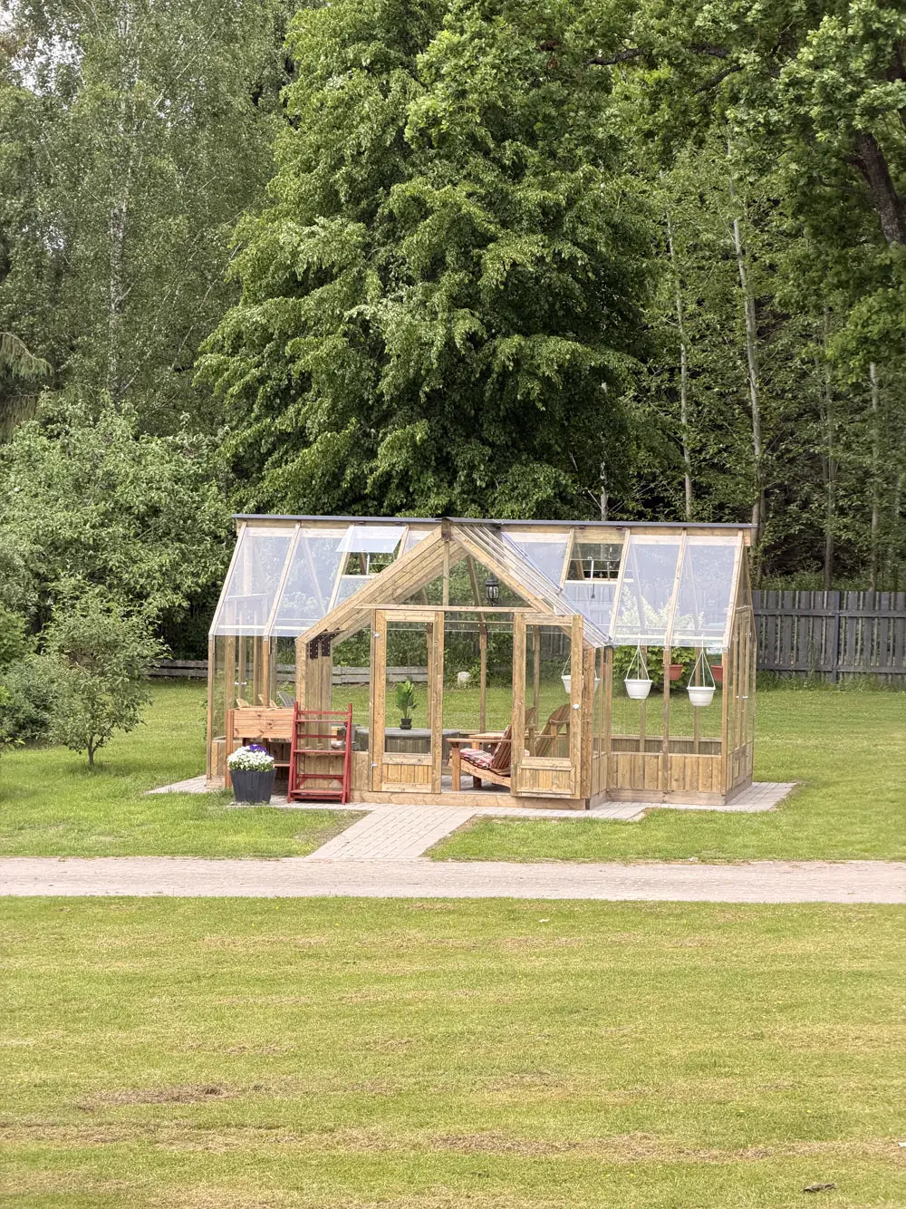 Greenhouse standing on a mown lawn with garden beds